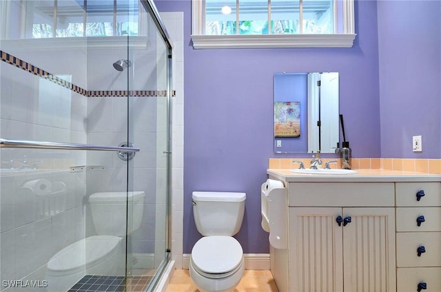 bathroom with vanity, toilet, and a shower with door