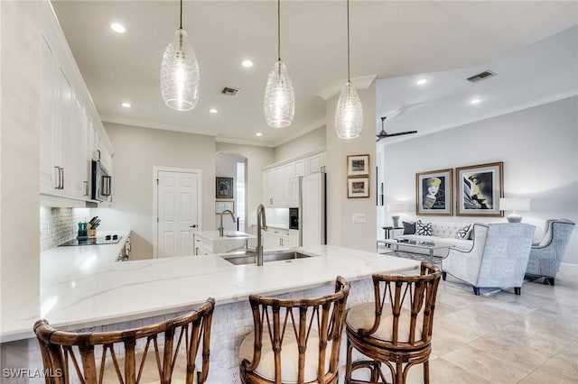 kitchen featuring paneled built in fridge, decorative light fixtures, kitchen peninsula, and sink