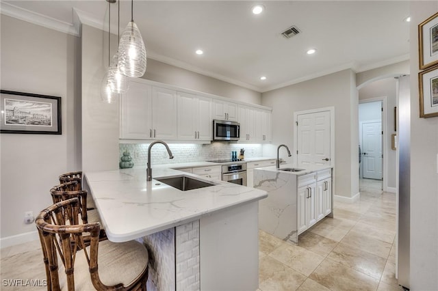 kitchen featuring stainless steel appliances, sink, white cabinets, and kitchen peninsula