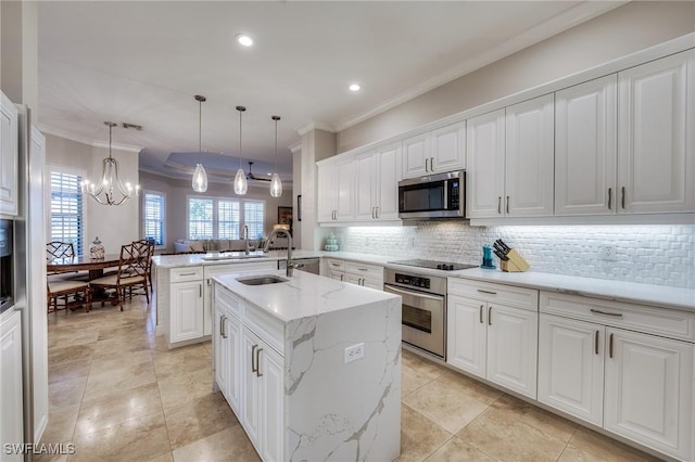 kitchen featuring appliances with stainless steel finishes, decorative light fixtures, white cabinets, kitchen peninsula, and a center island with sink