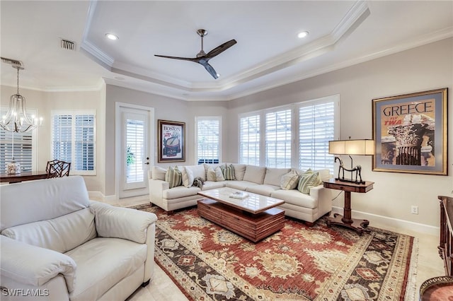 living room featuring ornamental molding, ceiling fan with notable chandelier, and a tray ceiling