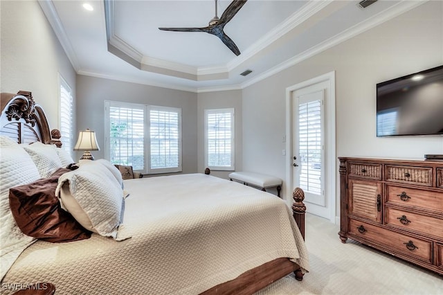 carpeted bedroom with ceiling fan, ornamental molding, a raised ceiling, and multiple windows