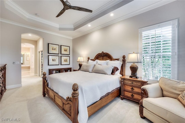 carpeted bedroom featuring ornamental molding, a tray ceiling, and multiple windows