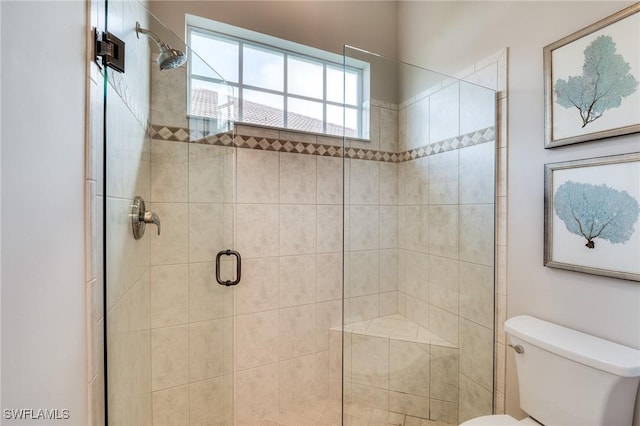 bathroom with a shower with shower door and toilet