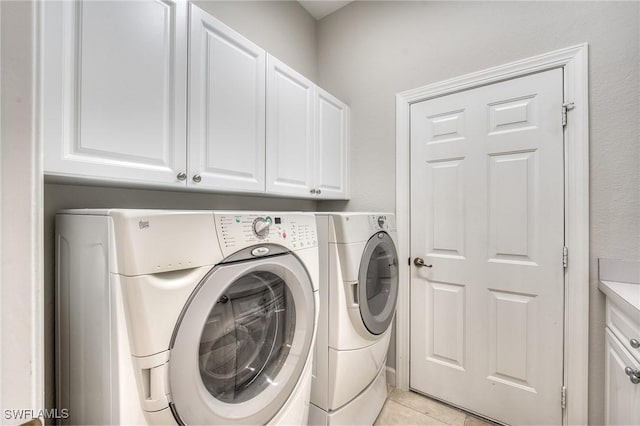 clothes washing area with cabinets, light tile patterned flooring, and independent washer and dryer