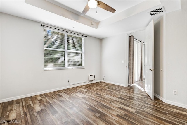 empty room featuring ceiling fan, dark hardwood / wood-style floors, and a raised ceiling