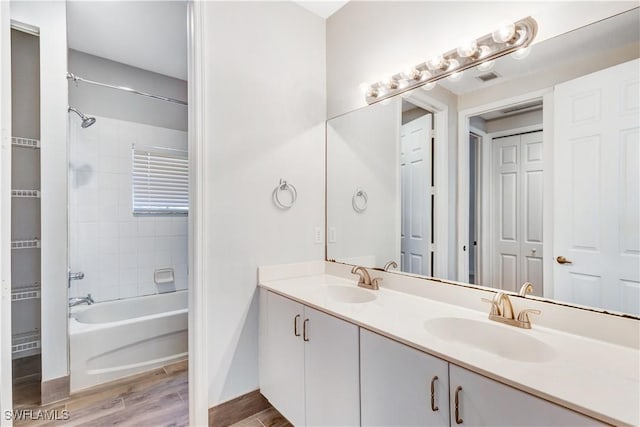 bathroom featuring hardwood / wood-style flooring, tiled shower / bath, and vanity