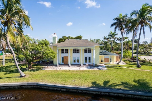 rear view of property featuring french doors and a lawn