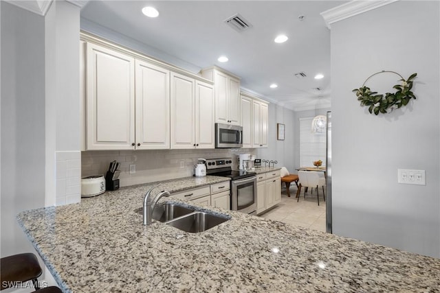 kitchen with stainless steel appliances, a sink, crown molding, tasteful backsplash, and light stone counters