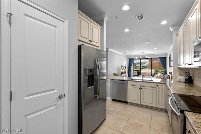 kitchen with appliances with stainless steel finishes, crown molding, cream cabinetry, recessed lighting, and light tile patterned floors