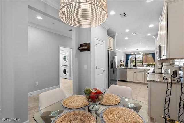 dining room with estacked washer and dryer, light tile patterned floors, recessed lighting, crown molding, and baseboards
