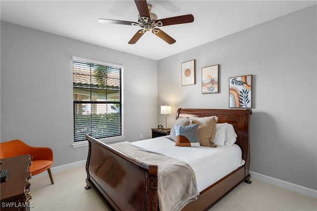bedroom featuring light colored carpet, baseboards, and a ceiling fan
