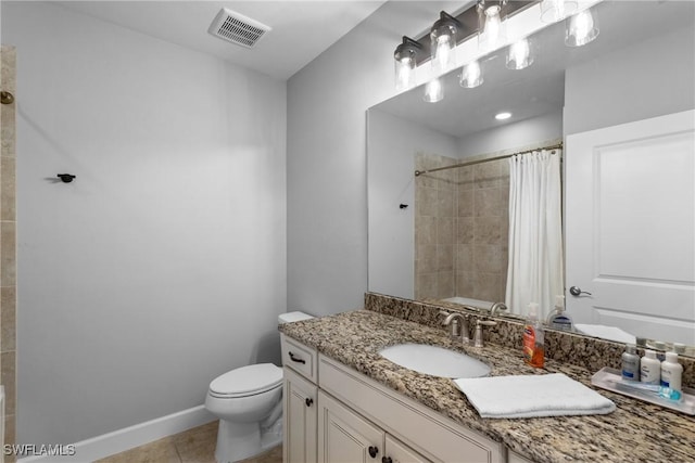 bathroom featuring a tile shower, tile patterned flooring, toilet, vanity, and baseboards