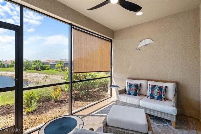 sunroom featuring ceiling fan, outdoor lounge area, and a water view