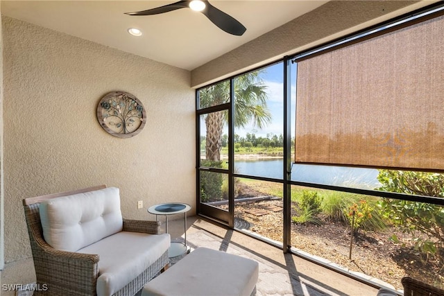 living area featuring a textured wall, a water view, a ceiling fan, and recessed lighting