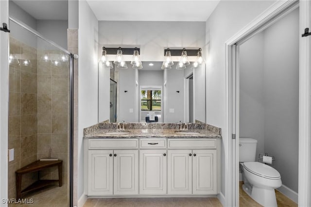 bathroom featuring a shower stall, double vanity, and toilet