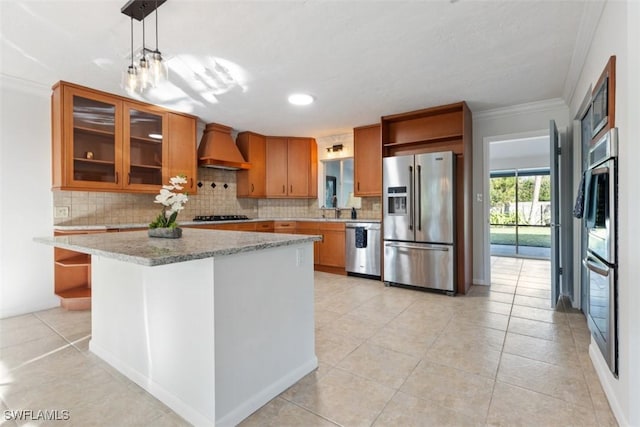 kitchen with appliances with stainless steel finishes, a center island, light stone counters, decorative light fixtures, and custom exhaust hood