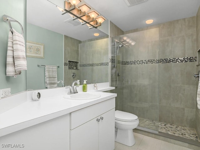 bathroom featuring vanity, tile patterned floors, toilet, and tiled shower