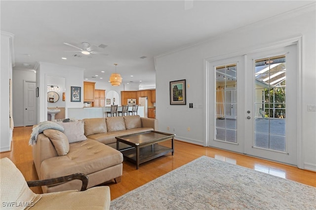 living room with light wood-style floors, recessed lighting, french doors, and crown molding