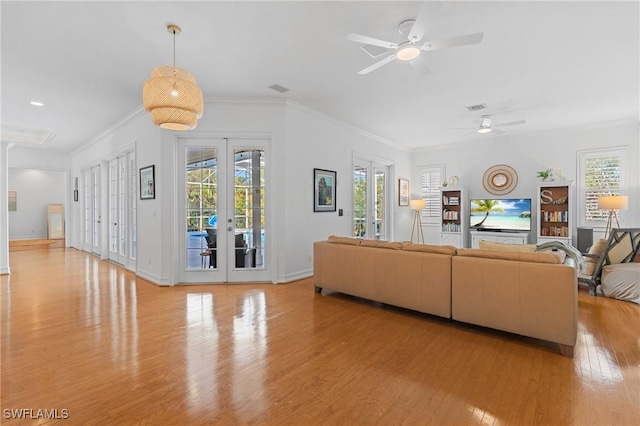 living area with baseboards, visible vents, crown molding, french doors, and light wood-style floors