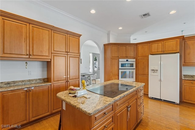 kitchen featuring white appliances, a kitchen island, visible vents, and light wood finished floors