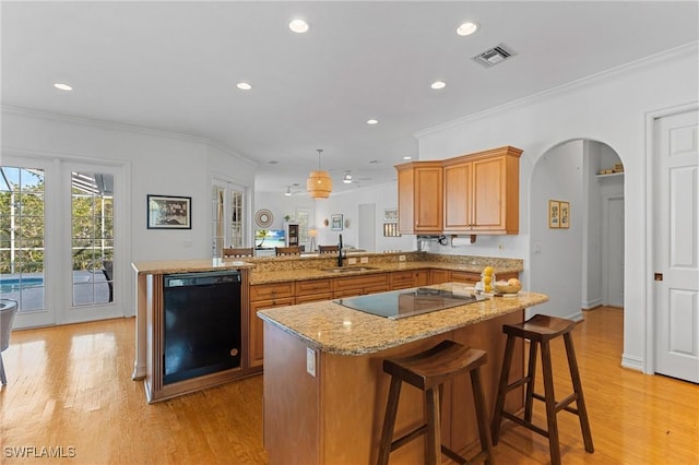 kitchen with visible vents, arched walkways, a breakfast bar area, a peninsula, and black appliances