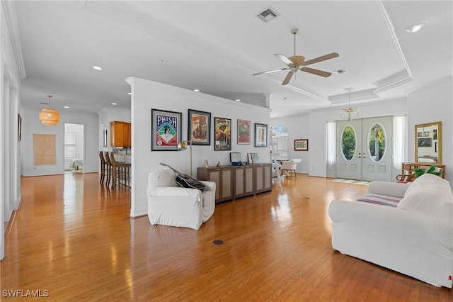 living room with crown molding, recessed lighting, a raised ceiling, visible vents, and light wood-style flooring