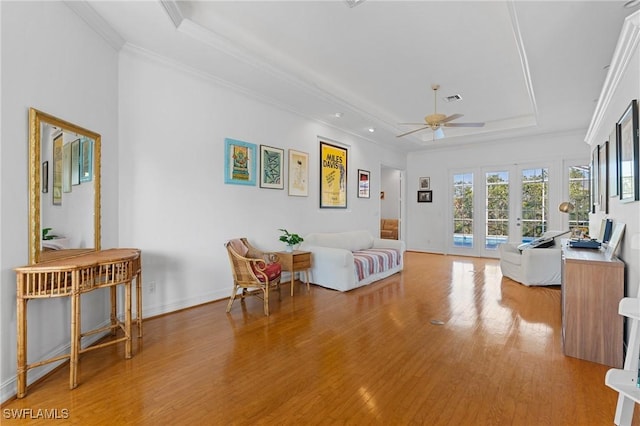 interior space with french doors, a raised ceiling, light wood-style flooring, and crown molding