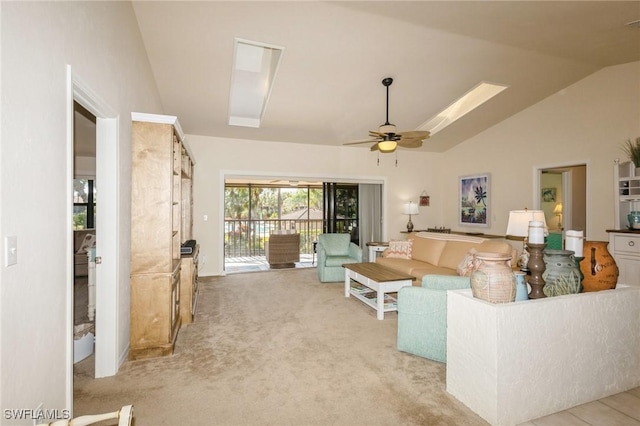 living room with ceiling fan, carpet flooring, and vaulted ceiling with skylight