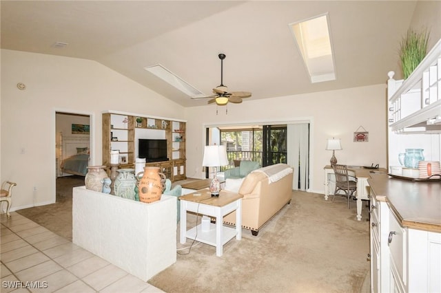 tiled living room with ceiling fan and vaulted ceiling with skylight