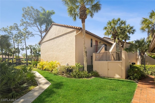 view of property exterior featuring a balcony and a lawn