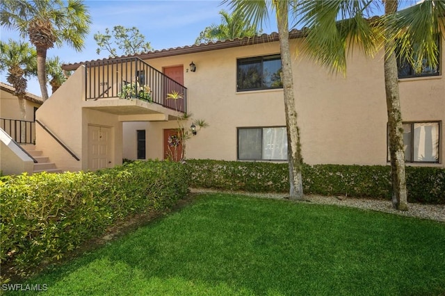 back of house with a balcony and a yard