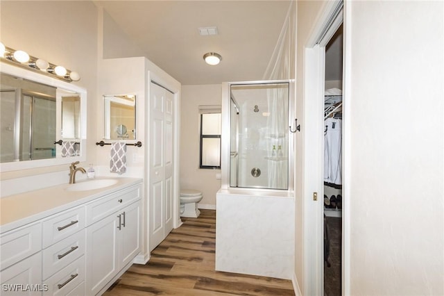 bathroom with toilet, hardwood / wood-style floors, vanity, and walk in shower