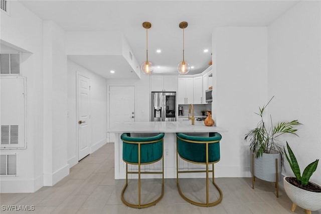 kitchen featuring appliances with stainless steel finishes, white cabinetry, a breakfast bar area, hanging light fixtures, and kitchen peninsula