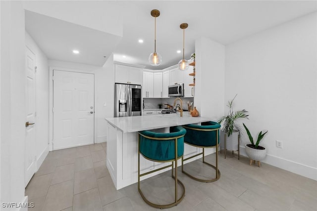 kitchen with a breakfast bar, kitchen peninsula, pendant lighting, stainless steel appliances, and white cabinets