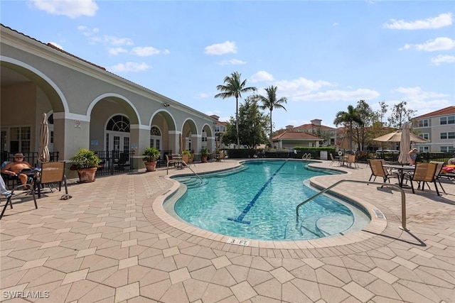 pool featuring french doors, a patio area, and fence