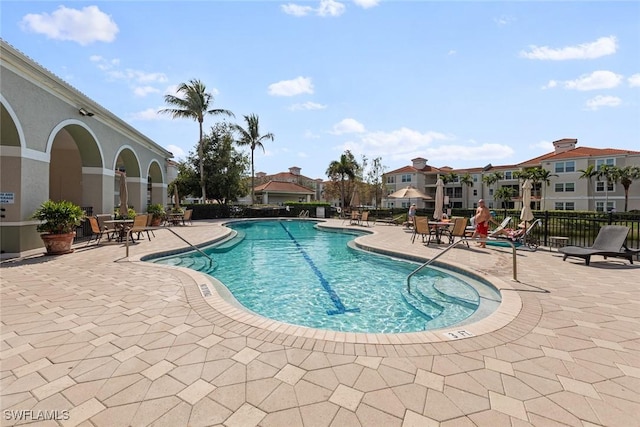 community pool with a patio, fence, and a residential view