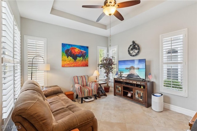 tiled living room featuring ceiling fan and a tray ceiling