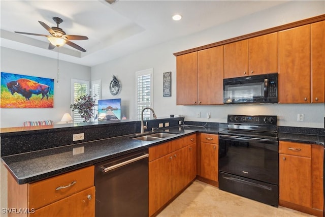 kitchen featuring sink, ceiling fan, dark stone countertops, a tray ceiling, and black appliances