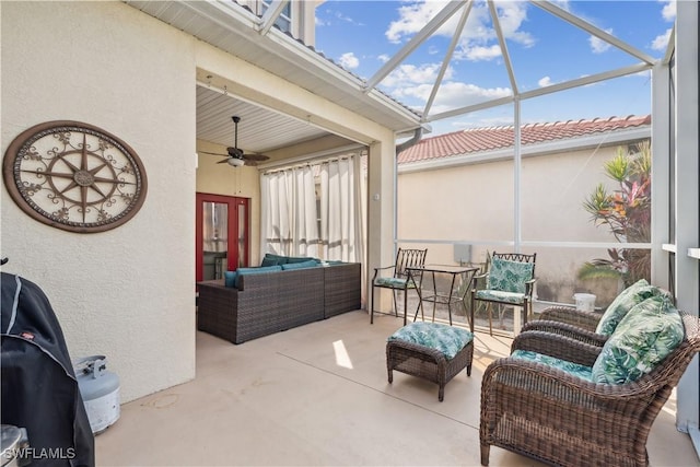 view of patio with area for grilling, an outdoor living space, ceiling fan, and glass enclosure