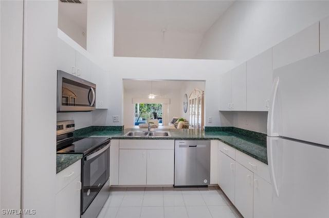 kitchen with sink, light tile patterned floors, appliances with stainless steel finishes, kitchen peninsula, and white cabinets