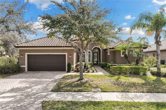 mediterranean / spanish-style house featuring a garage and a front lawn