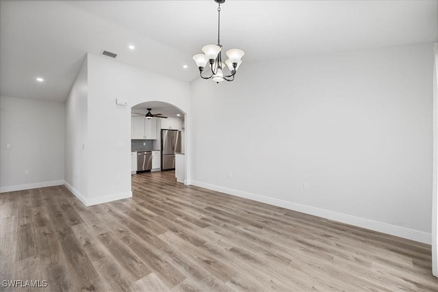 unfurnished room with arched walkways, light wood-style flooring, recessed lighting, ceiling fan with notable chandelier, and baseboards