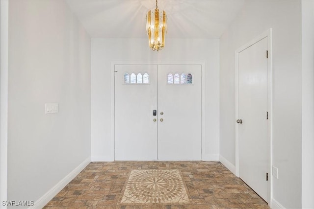 foyer entrance featuring a chandelier and baseboards