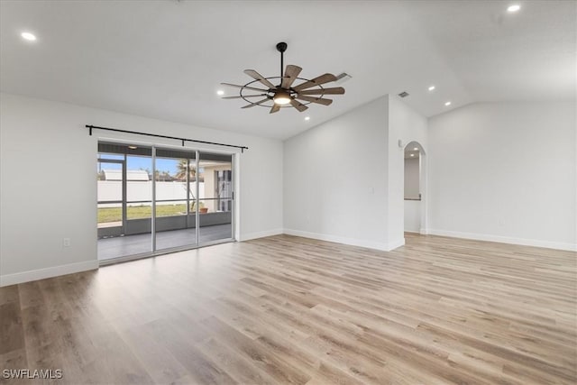 spare room featuring ceiling fan, arched walkways, baseboards, vaulted ceiling, and light wood finished floors