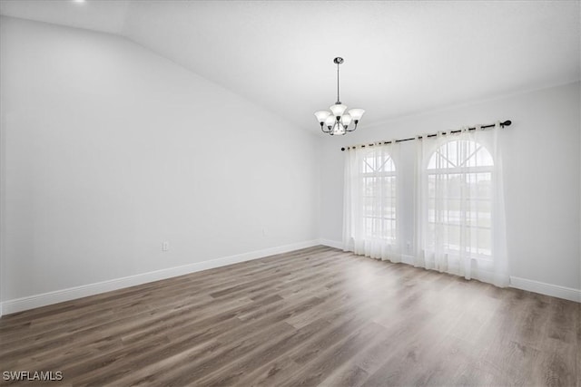 unfurnished room with dark wood-style floors, vaulted ceiling, baseboards, and an inviting chandelier