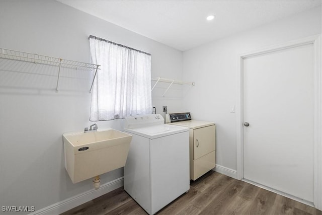 laundry area featuring laundry area, baseboards, dark wood-type flooring, separate washer and dryer, and a sink