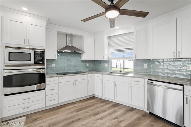 kitchen with white cabinets, wall chimney exhaust hood, stainless steel appliances, and a sink