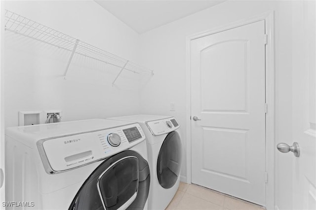 laundry room featuring washer and clothes dryer and light tile patterned flooring