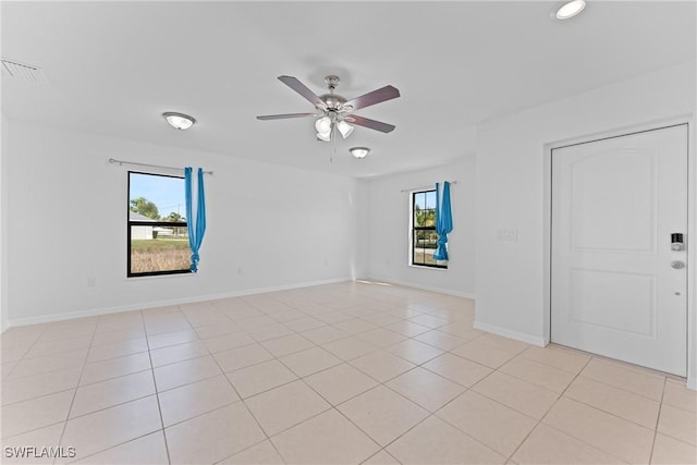 tiled empty room featuring plenty of natural light and ceiling fan